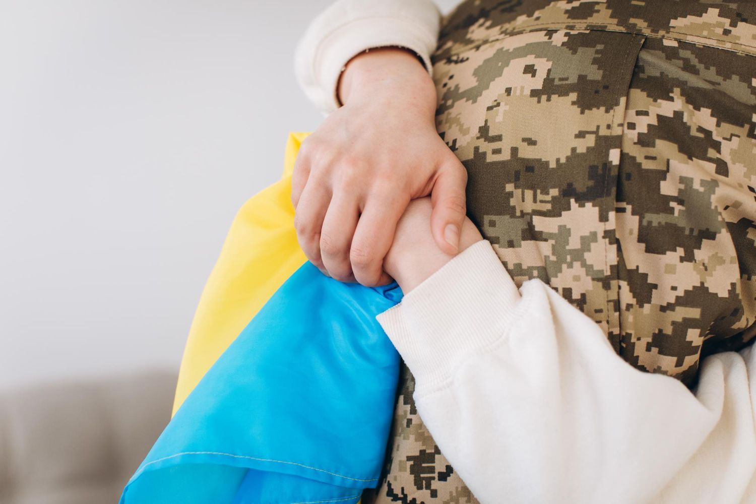 Дитина обіймає військового з українським прапором — єОселя для захисників